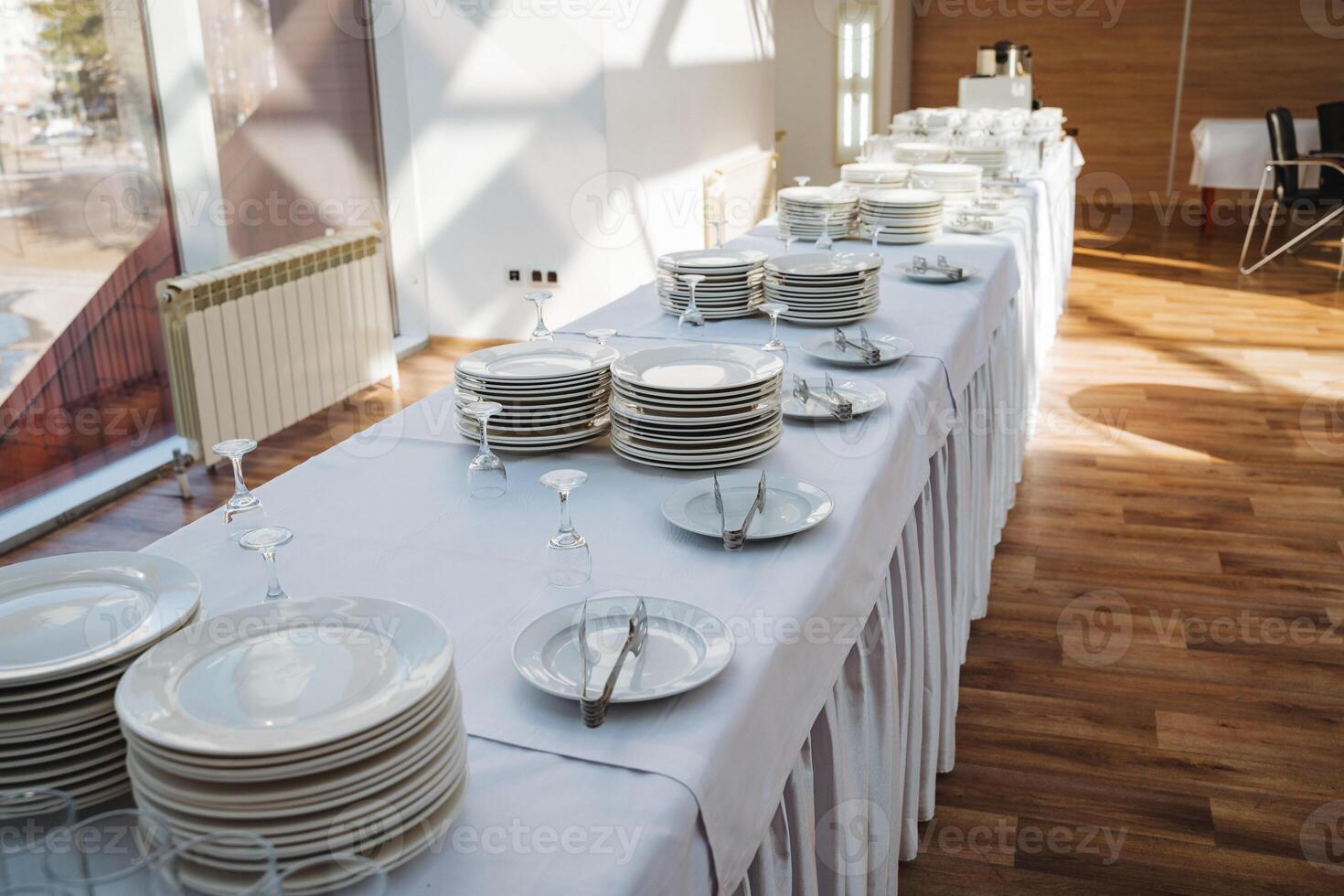 There is a long table beautifully set with plates, glasses, and silverware arranged neatly on it, creating an inviting atmosphere for dining or gathering with friends or family photo