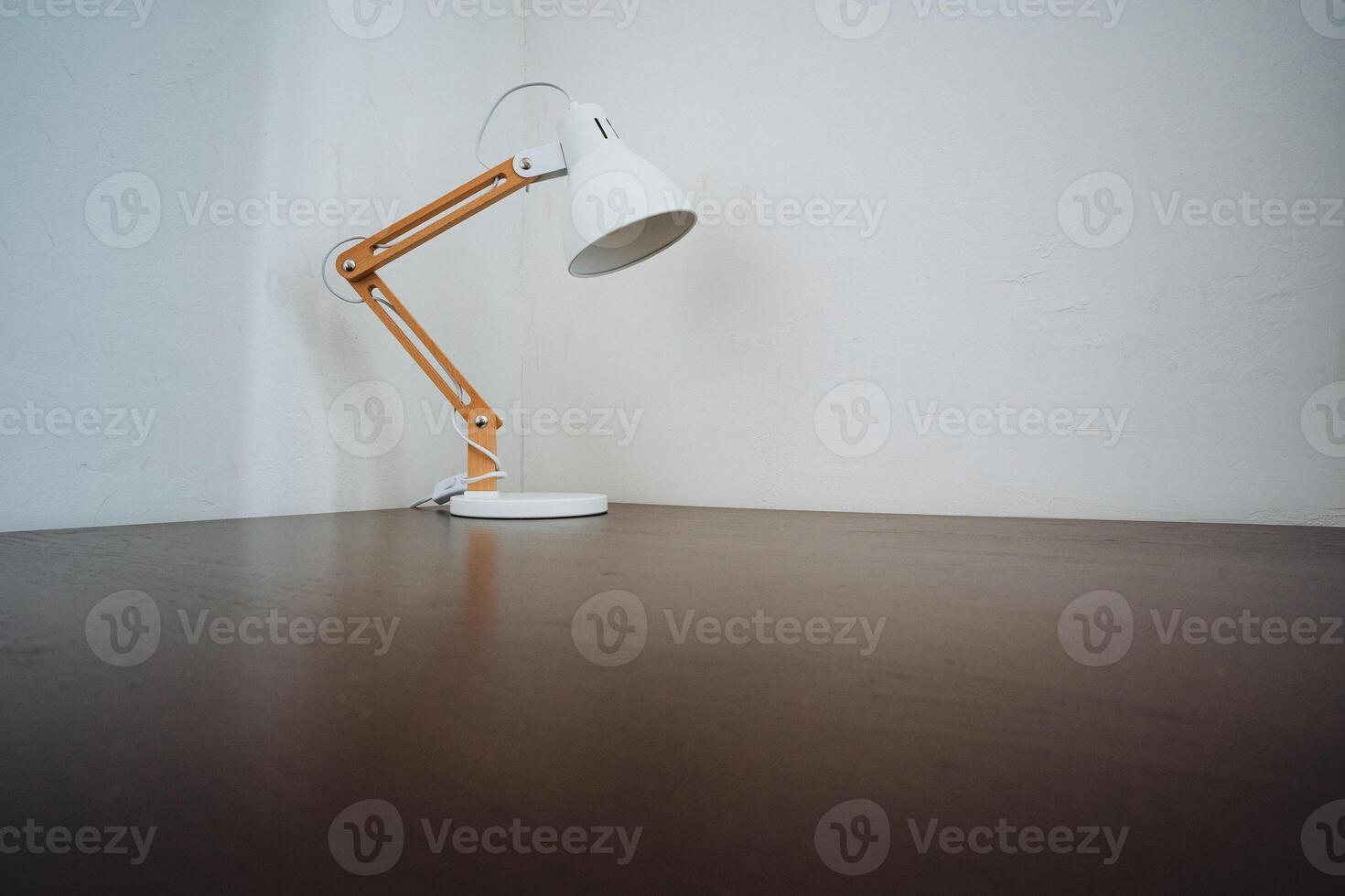 The elegant white lamp on the sturdy wooden table casts a warm glow, illuminating the room and adding character to the decor, enhancing the cozy atmosphere significantly photo