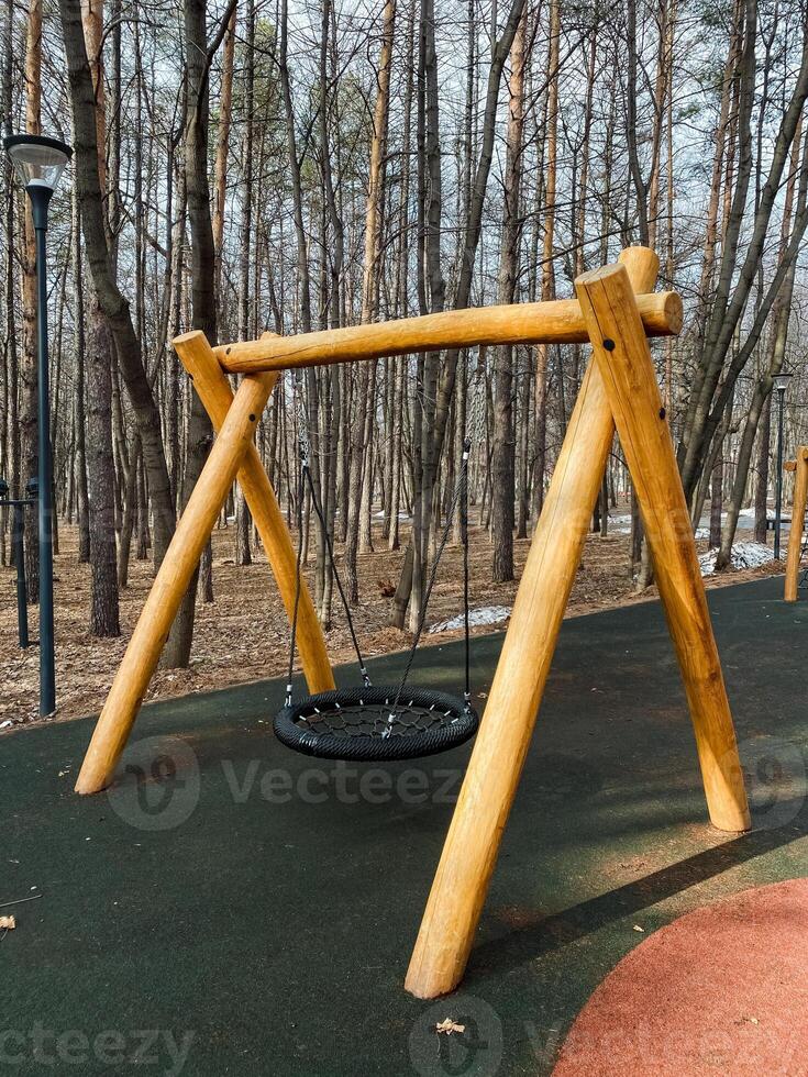 Experience a Unique Wooden Swing set in a Serene Forest Playground, perfect for adventure, relaxation, and mindfulness surrounded by lush greenery and beautiful landscaping photo