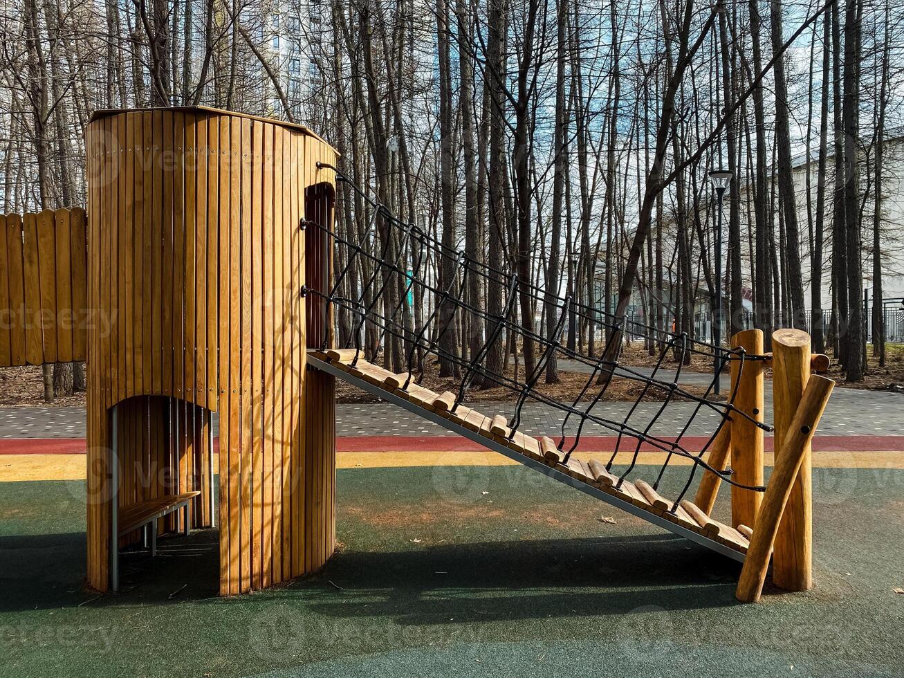 Introducing a Unique Wooden Playground Structure featuring a Climbing Rope, all set in a Serene Natural Setting. A perfect place for children to enjoy playtime and adventure photo