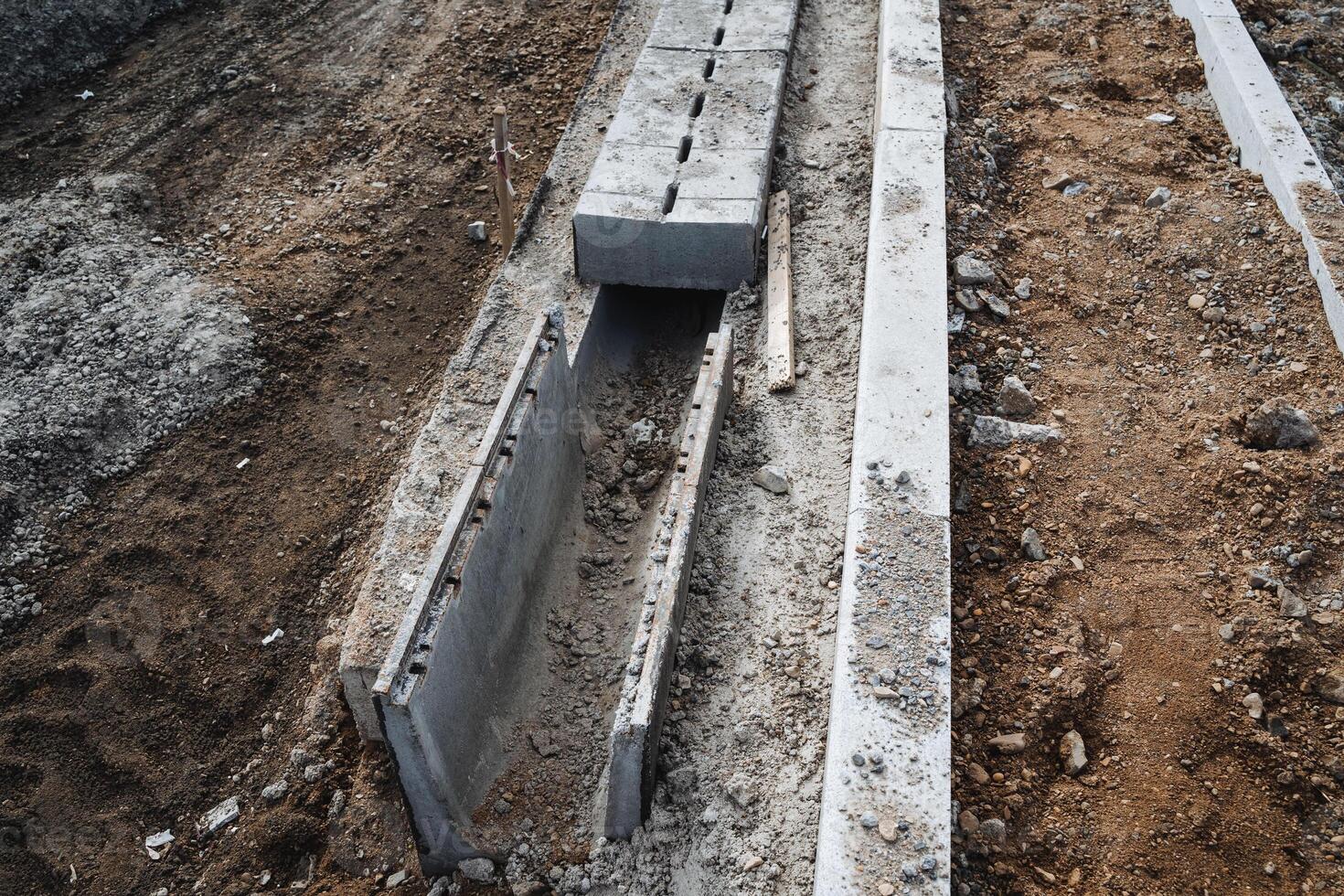 A concrete drain is currently under construction in the dirt, which is an essential part of the infrastructure being set up for various purposes such as agriculture and drainage photo
