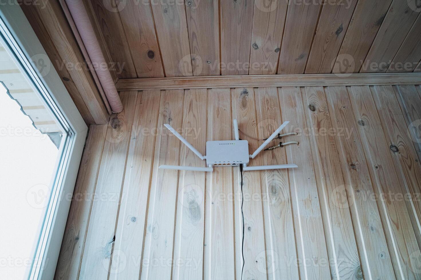 A router is securely mounted on a wooden wall that is situated right next to a large window which allows for natural light to fill the room, creating a bright and inviting atmosphere photo
