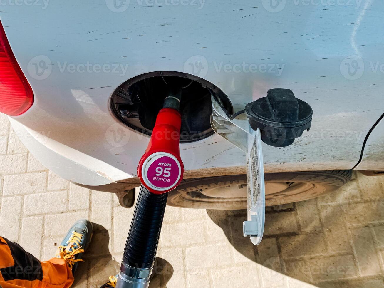 A closeup of a fuel pump and gas cap at a busy station showcases the convenience drivers find when refueling in urban areas, highlighting the need for quick fueling options photo