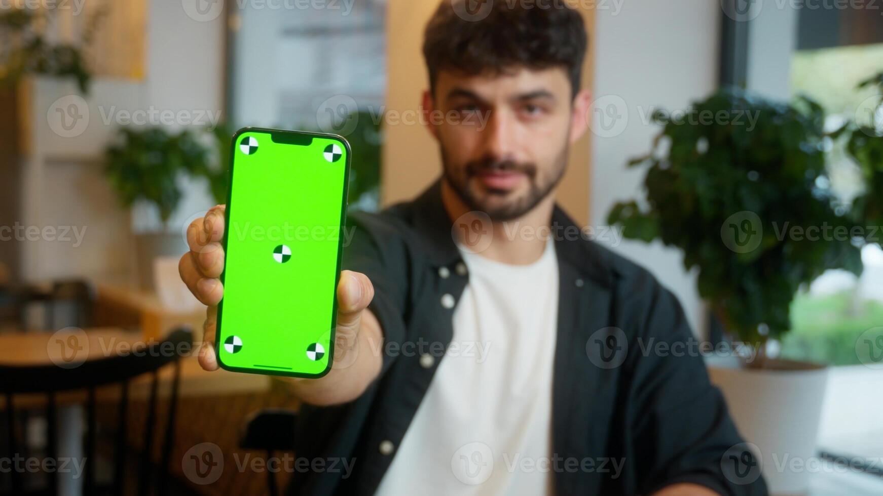 Caucasian man male guy shows mobile phone cafe smartphone cellphone green screen display restaurant chromakey template app online visitor customer businessman business website client internet service photo