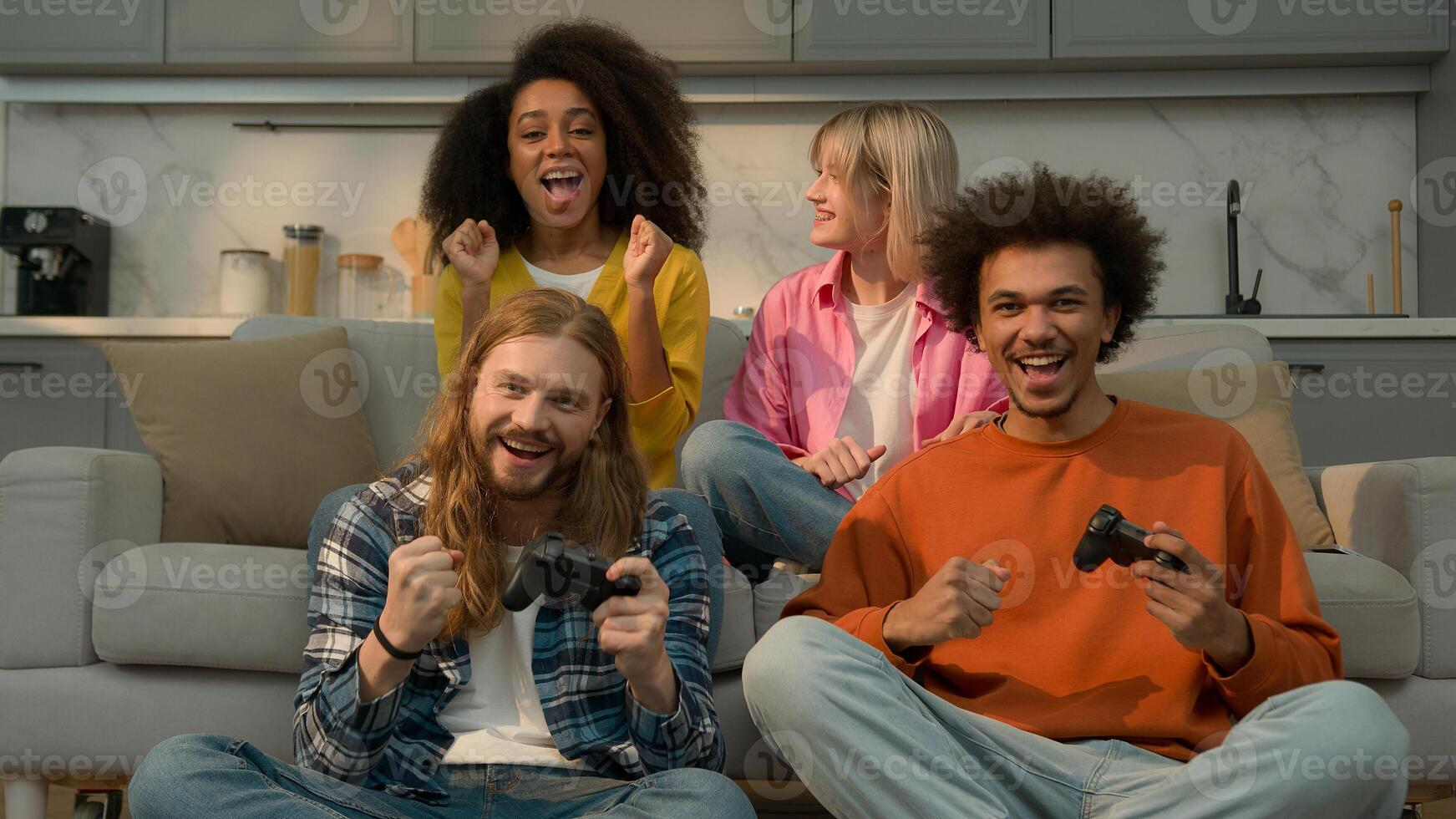 Four multiracial people friends students fun weekend at home Caucasian men guys males playing console game addicted win lost African American women girls females support laughing joy friendship photo