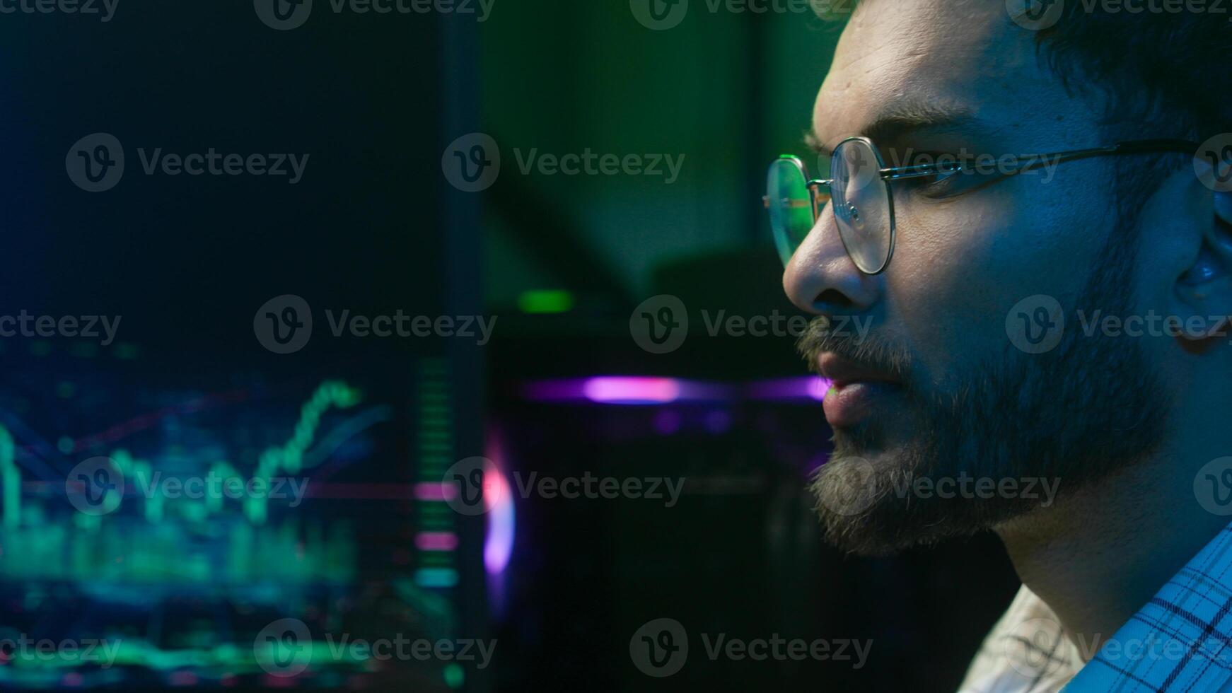 Close up Arabian Indian man analyzing pondering contemplating planning analyst programmer trader crypto currency male guy businessman business neon office professional IT specialist strategy keyboard photo