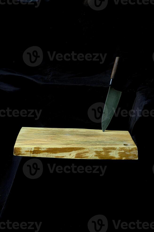 wooden cutting board and kitchen knife isolated on black background photo
