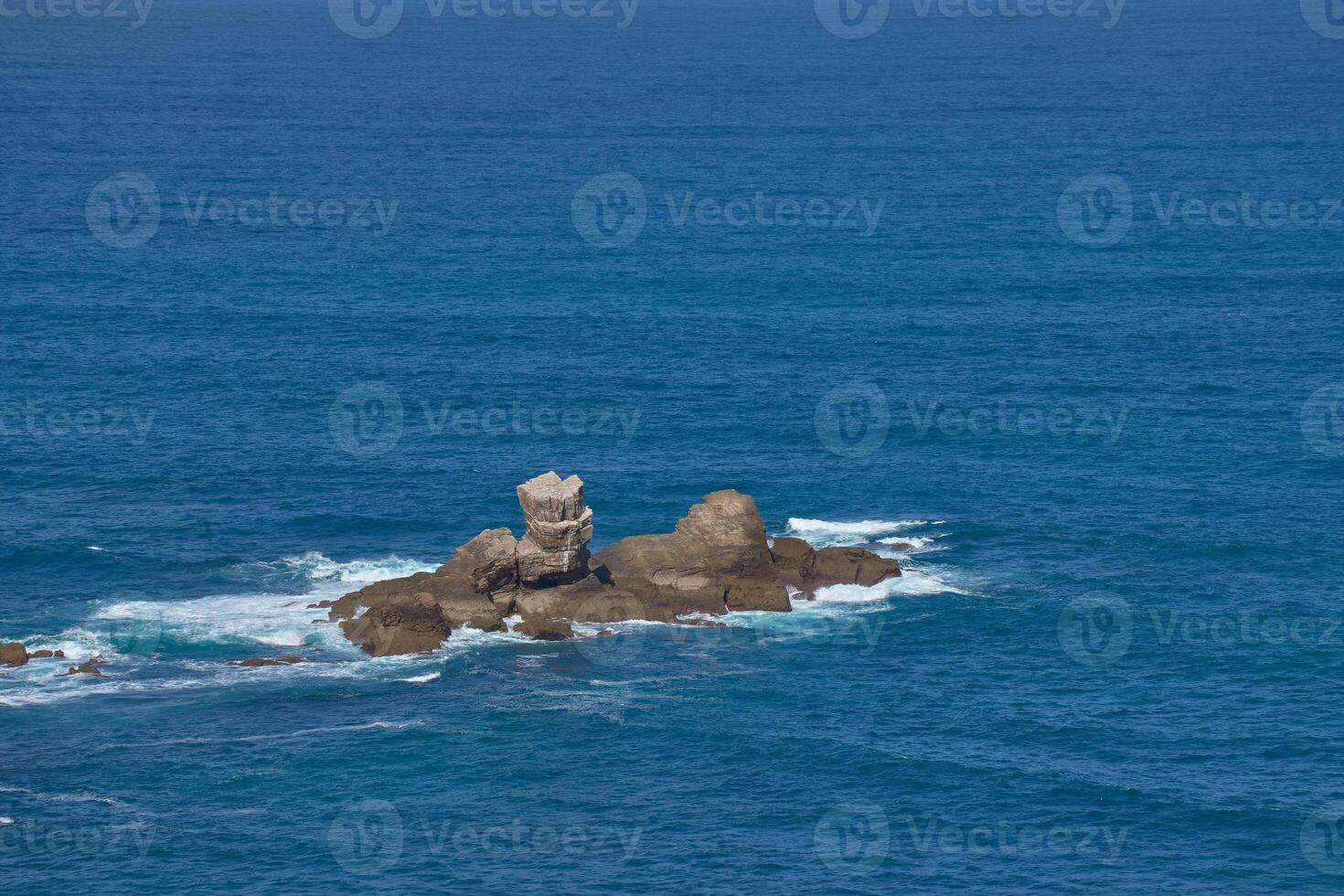 A small rocky islet seen from the Senda de Cadavedo in Cabo de Busto, Asturias, Spain photo