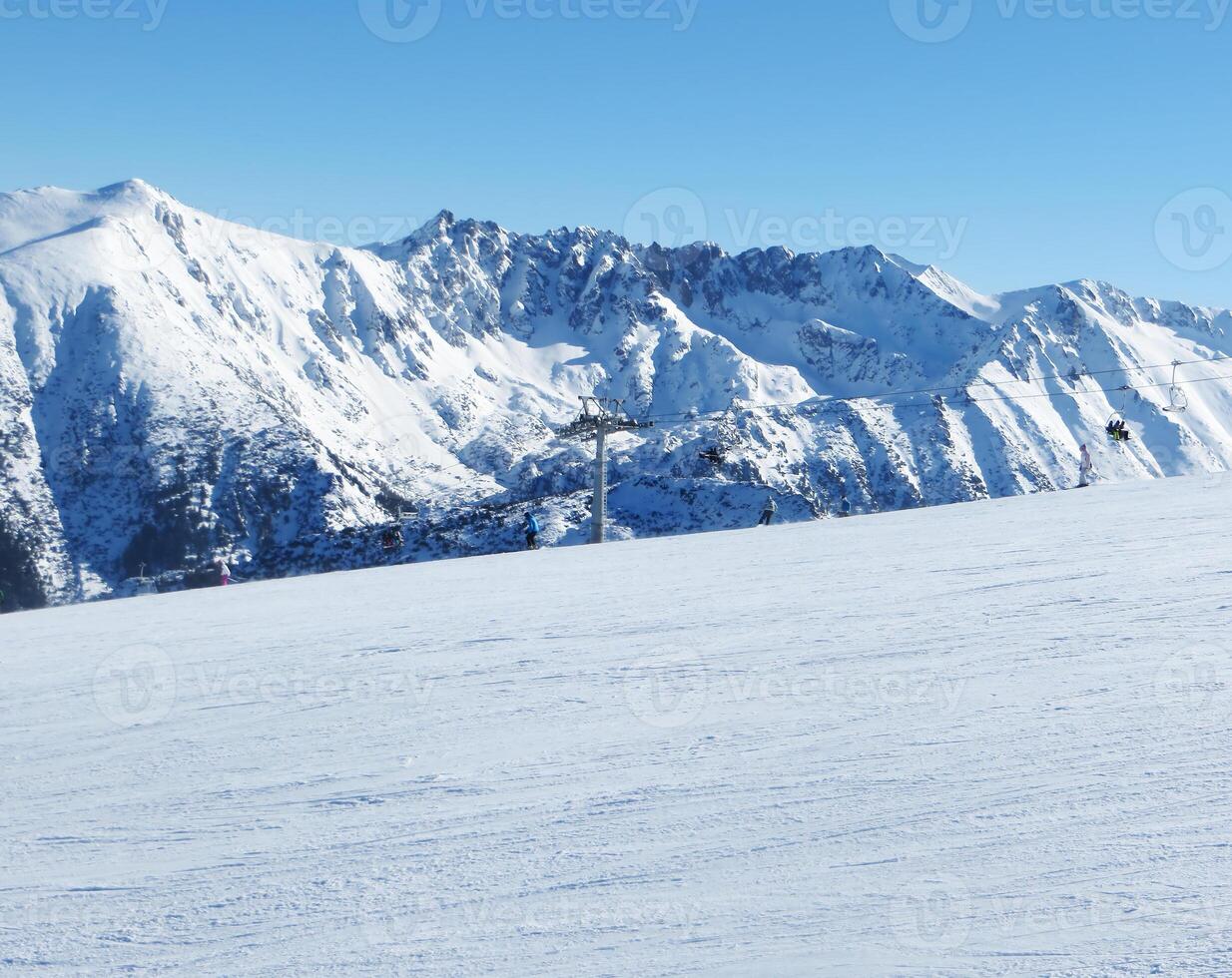 Winter in the mountains. Winter landscape with snow-capped mountains and skiers enjoying the speed and fresh frosty air. photo