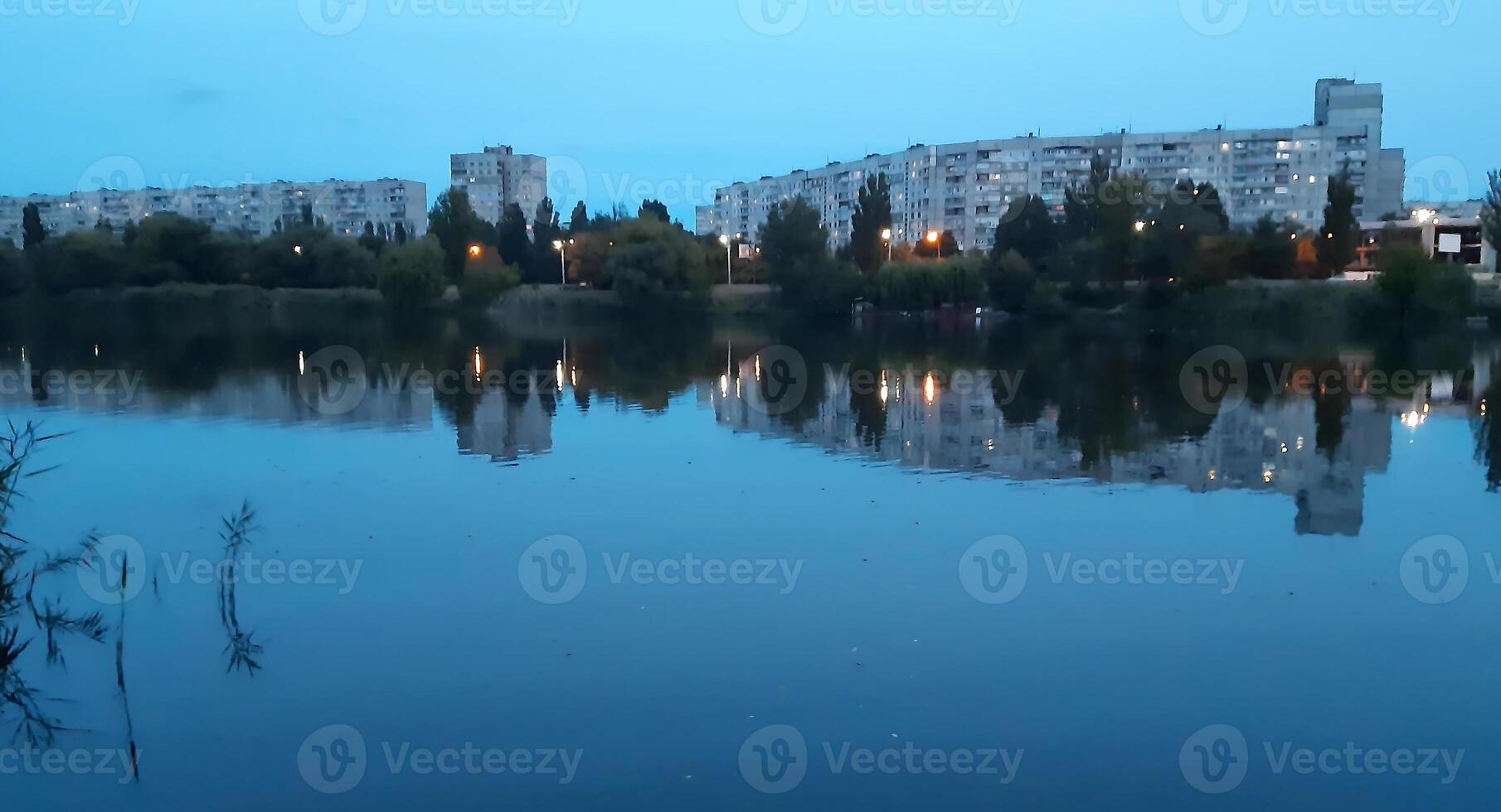 A cozy evening landscape on the outskirts of the city, above the river. A light breeze and quiet water overflows photo
