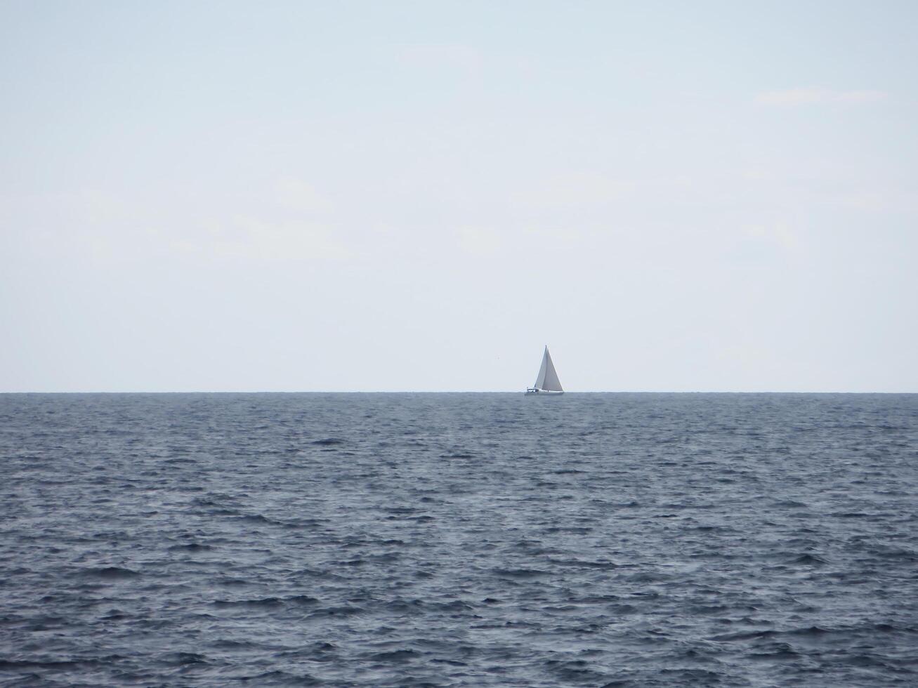 The boundless expanse of the sea with gentle waves shimmering in the sunlight. In the distance, on the horizon photo