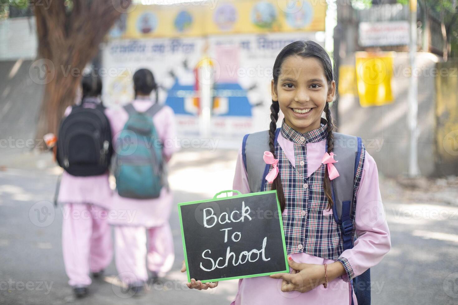 Innocent Girl Student In School Uniform With Crossed Arms Standing Beside The School photo