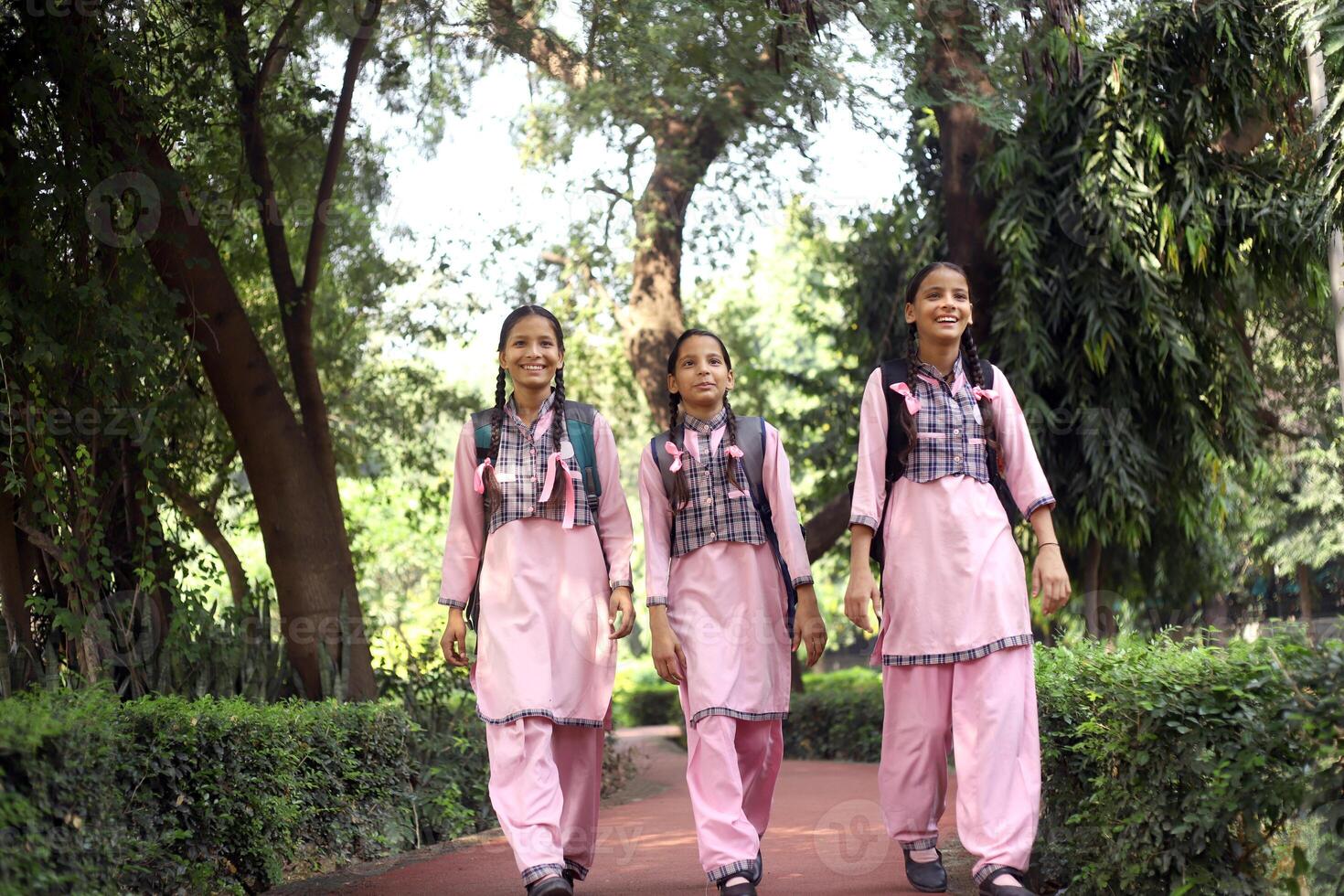 Three Teenage Girls Going To School And In Which One Of Whom Is Looking Back photo