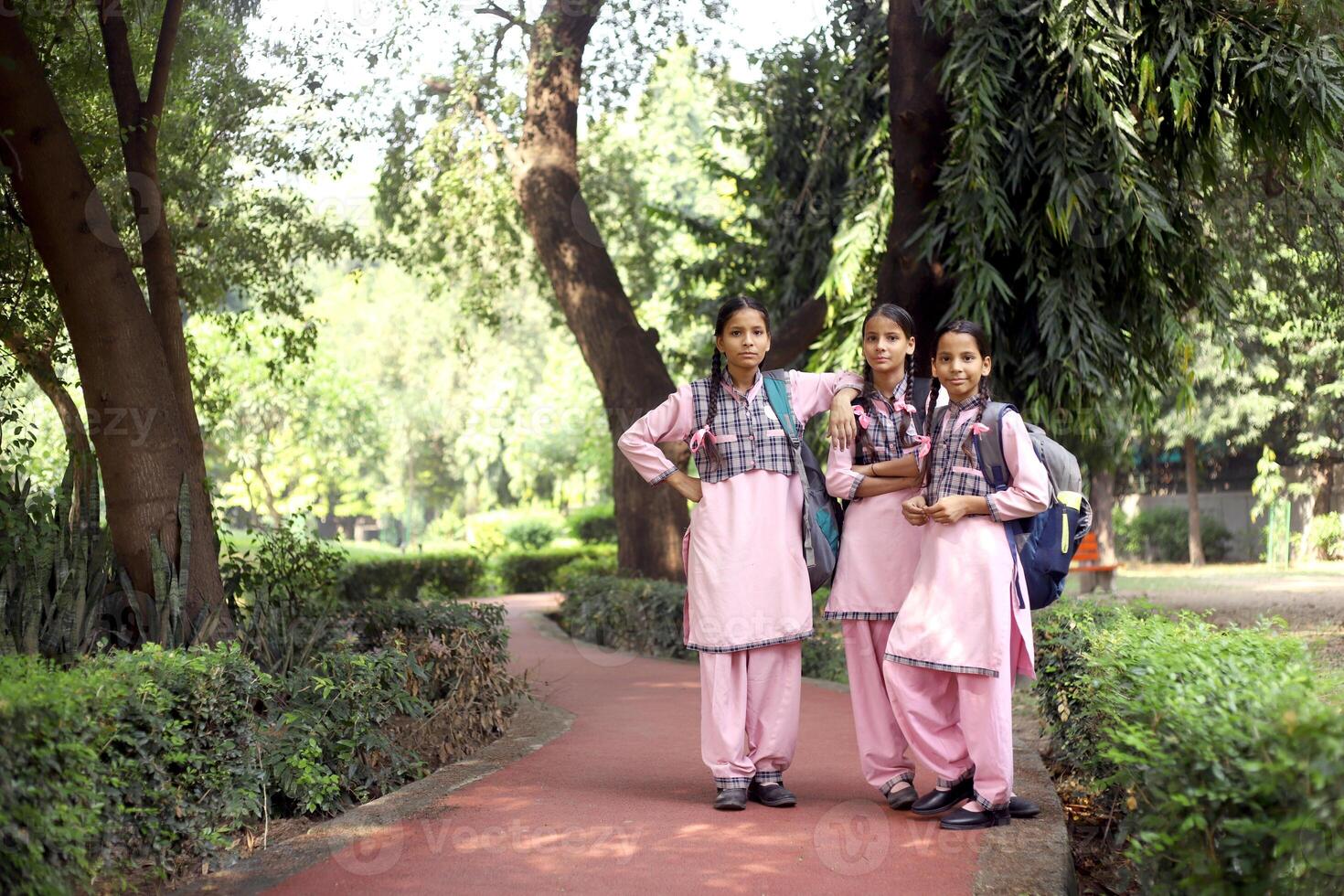 Indian Girls In School Dress Going To School And One Girl Looking Back Towards The Camera photo