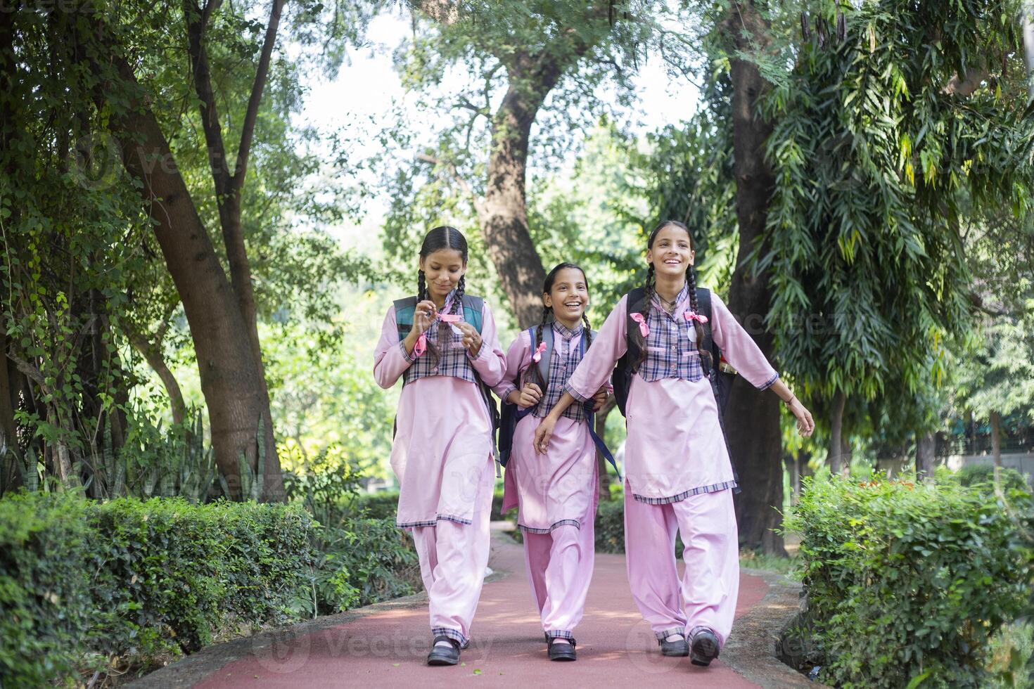 School Girls Eating Lunch From Lunchbox Sitting In School Playground photo