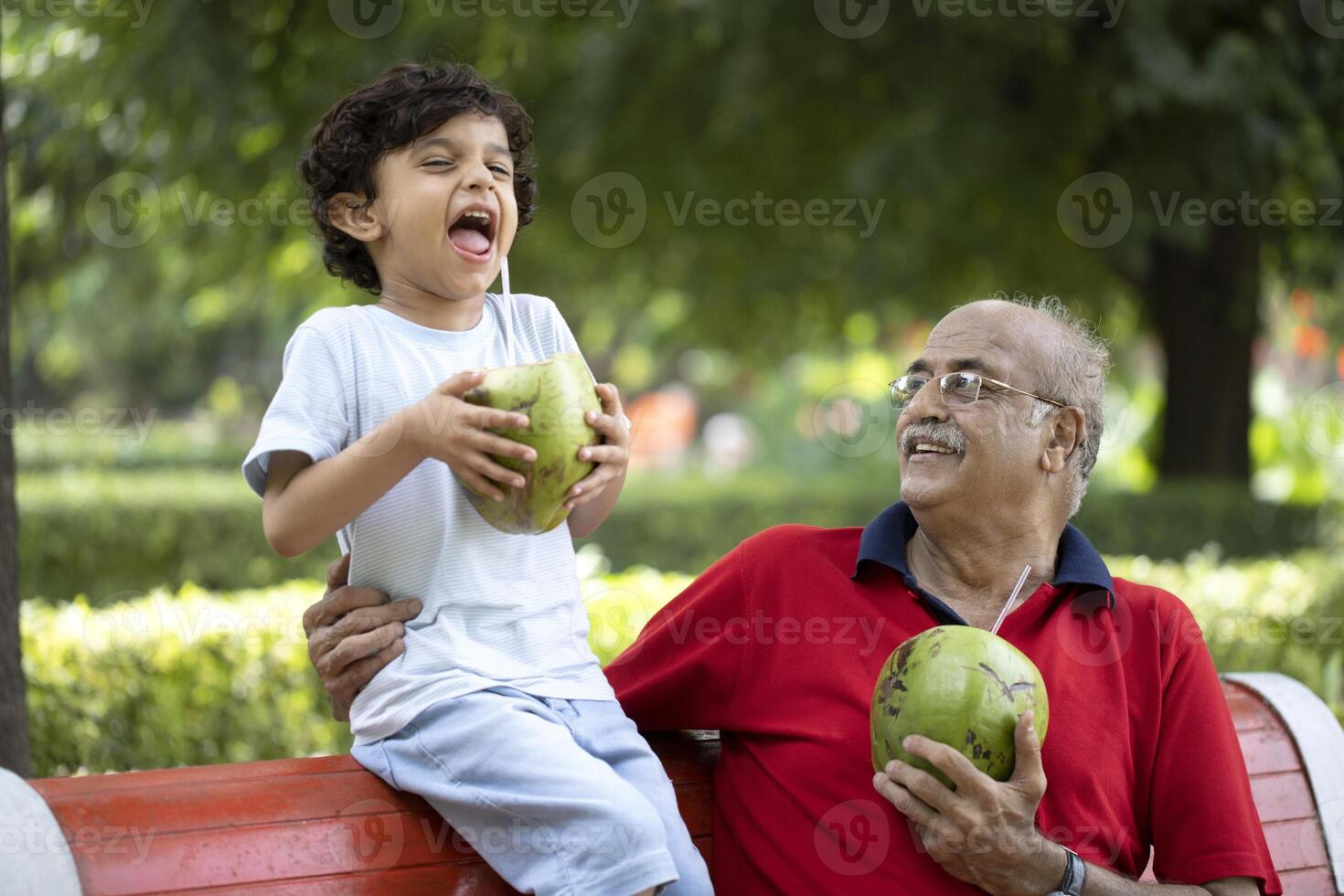 Happy Child Smiling While Drinking Tender Coconut Water With Grandpa photo