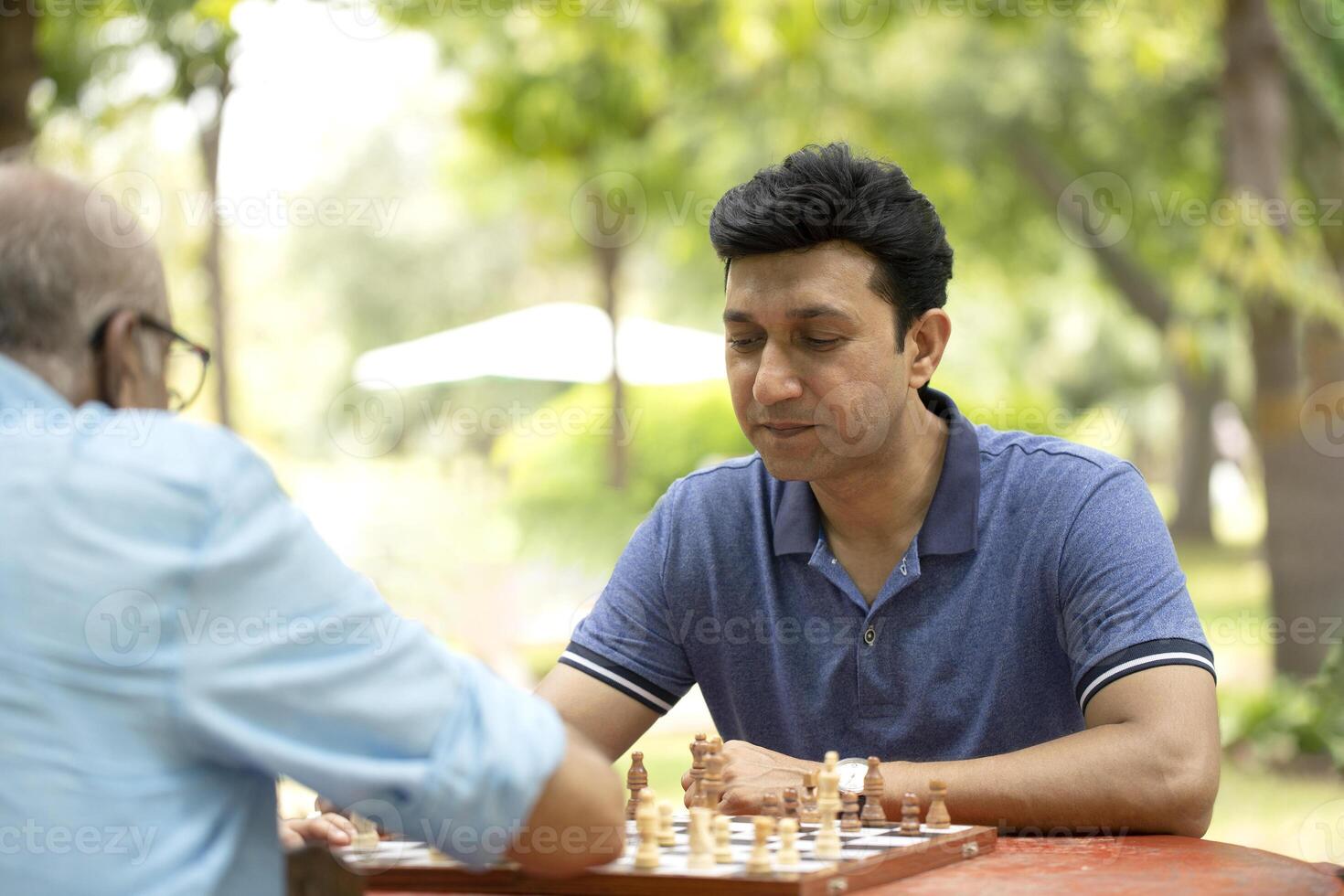 Mature Son Thinking While Playing Chess in the park photo