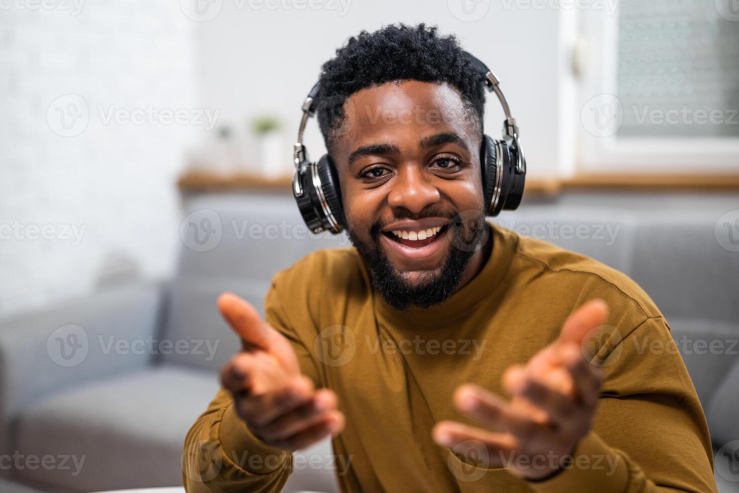 A close up portrait of professional African American entrepreneur gesturing while attending an online meeting, wearing headphones and working from home. photo