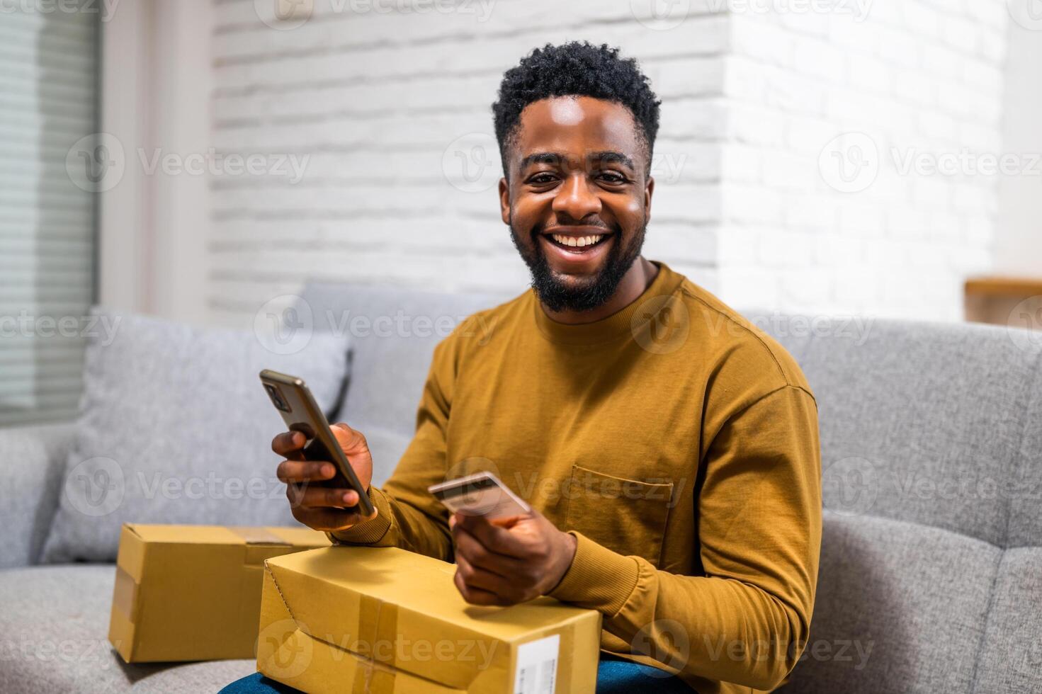 African American man using his smart phone to make online purchase. He is entering credit card information for home delivery service. photo