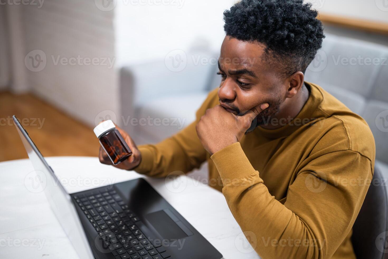 African American man looks concerned while researching his symptoms on a laptop, exploring possible side effects of his medication and seeking professional guidance. photo