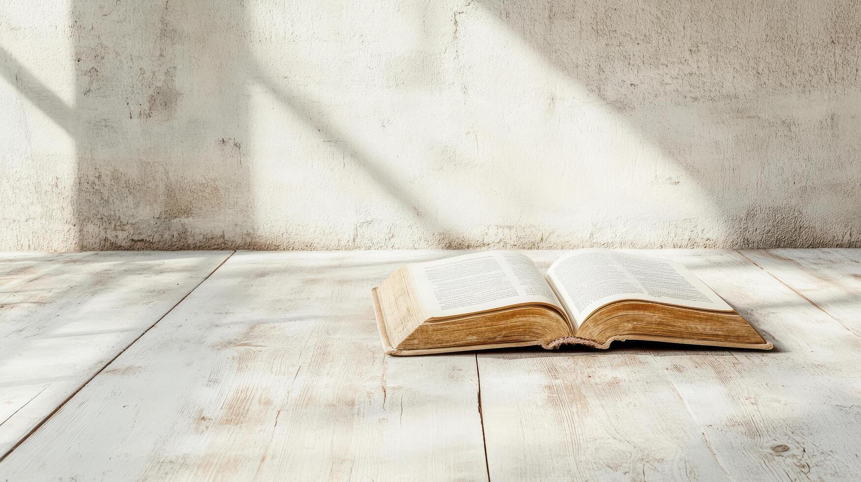 An open bible on a wooden floor in front of a wall photo