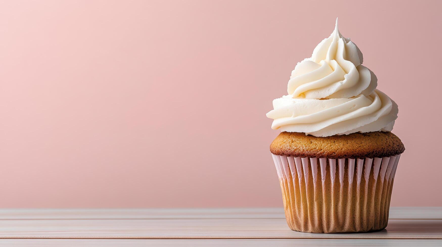 A cupcake with white frosting on top on a pink background photo