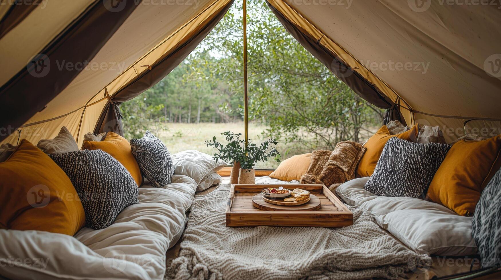 Cozy camping tent interior featuring soft cushions and wooden tray with snacks, creating warm and inviting atmosphere for relaxation in nature photo