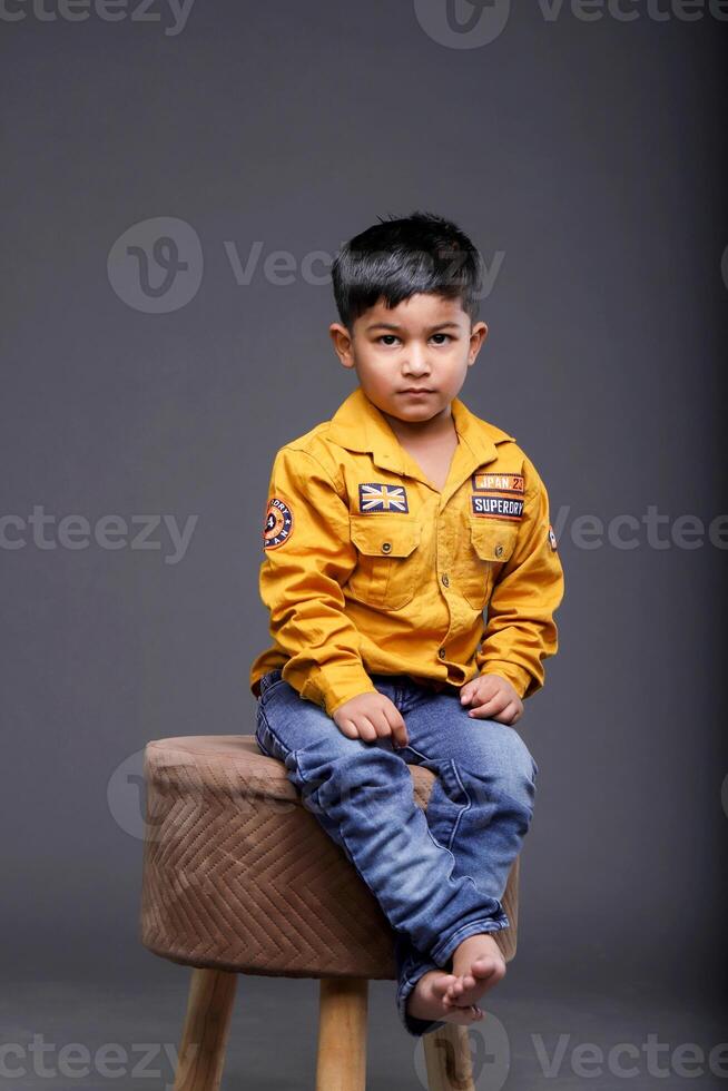 A Small Boy Sitting On A Stool Is Posing photo