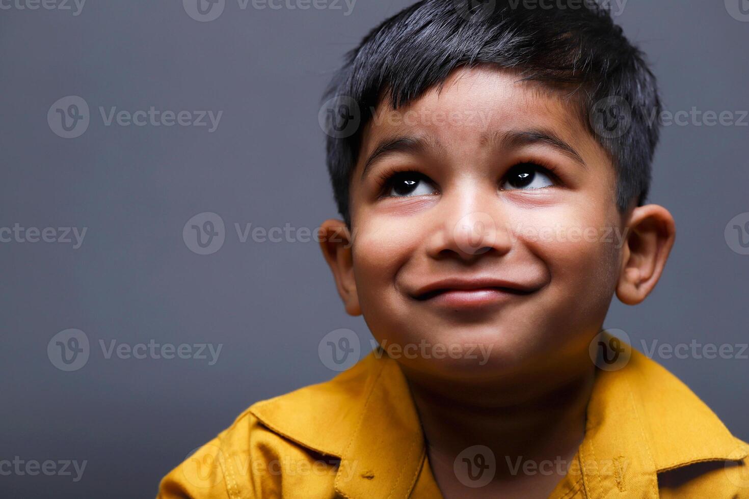Close-Up Shot Of A Little Kid Smiling And Looking Away photo