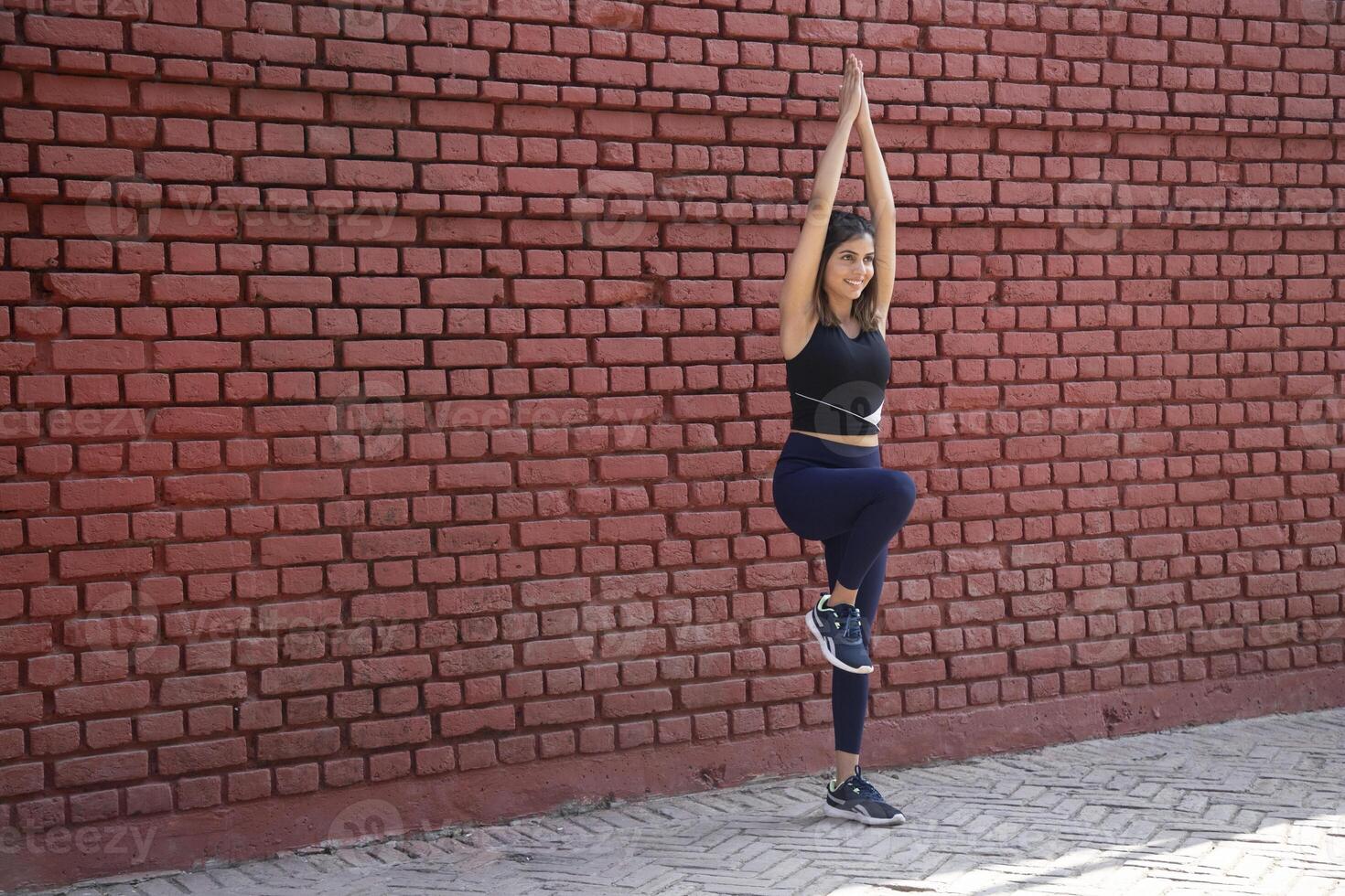 Fit Lady Standing On One Leg With Both Hands Up While Practising Body Balance photo