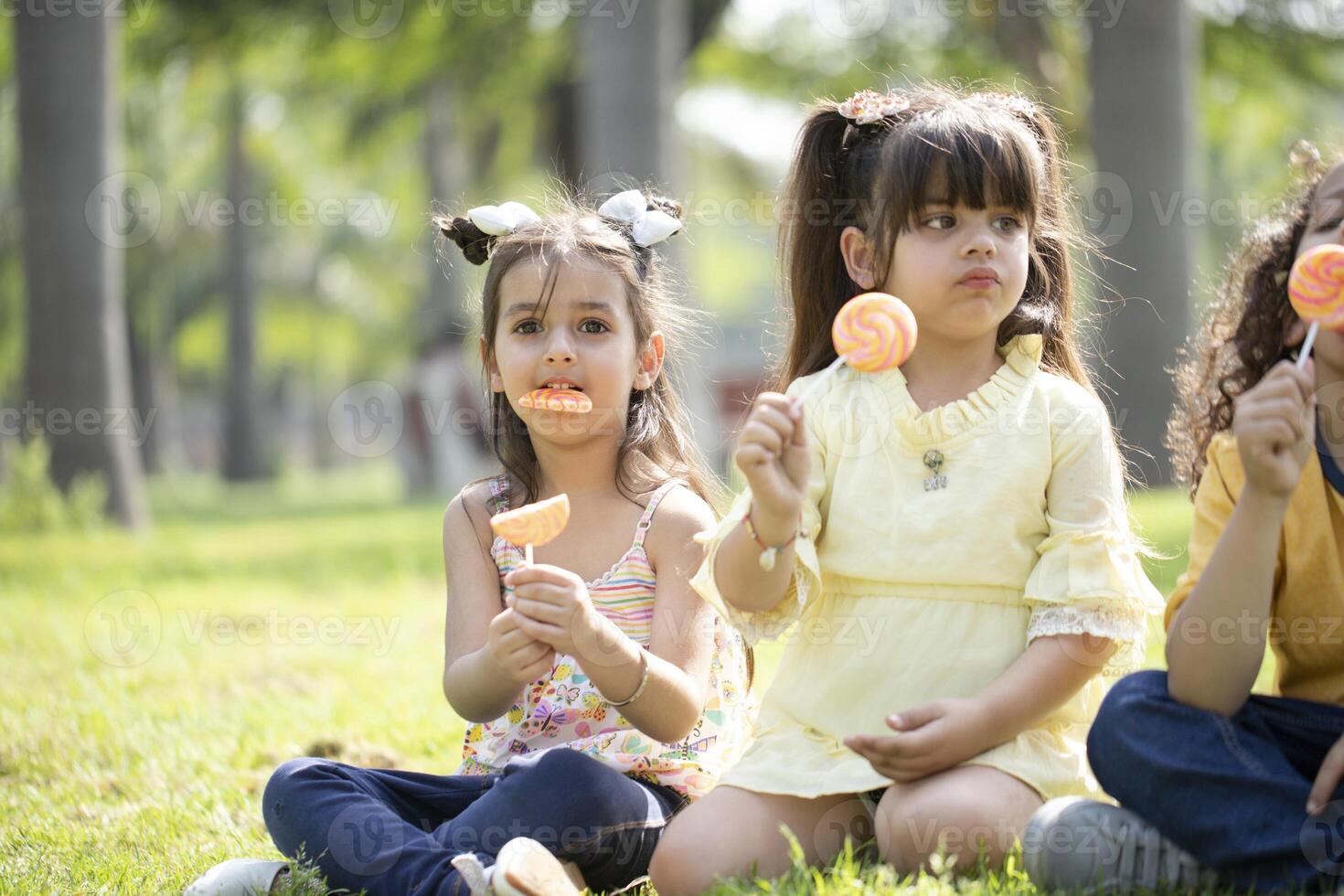 Three Little Friends Eating Lollipop photo
