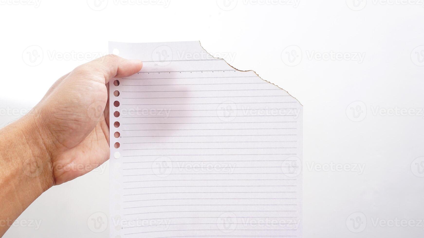 Hand holding stripped paper burns edge isolated on a white backgrounds photo