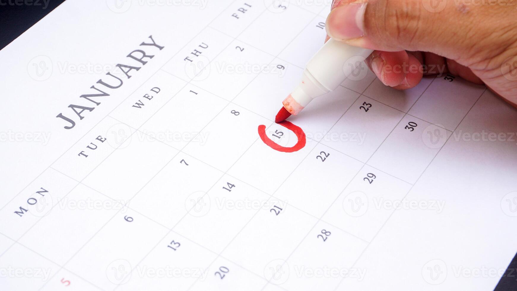 Red circle marked on a calendar at 15 of January isolated on black background for an important day photo