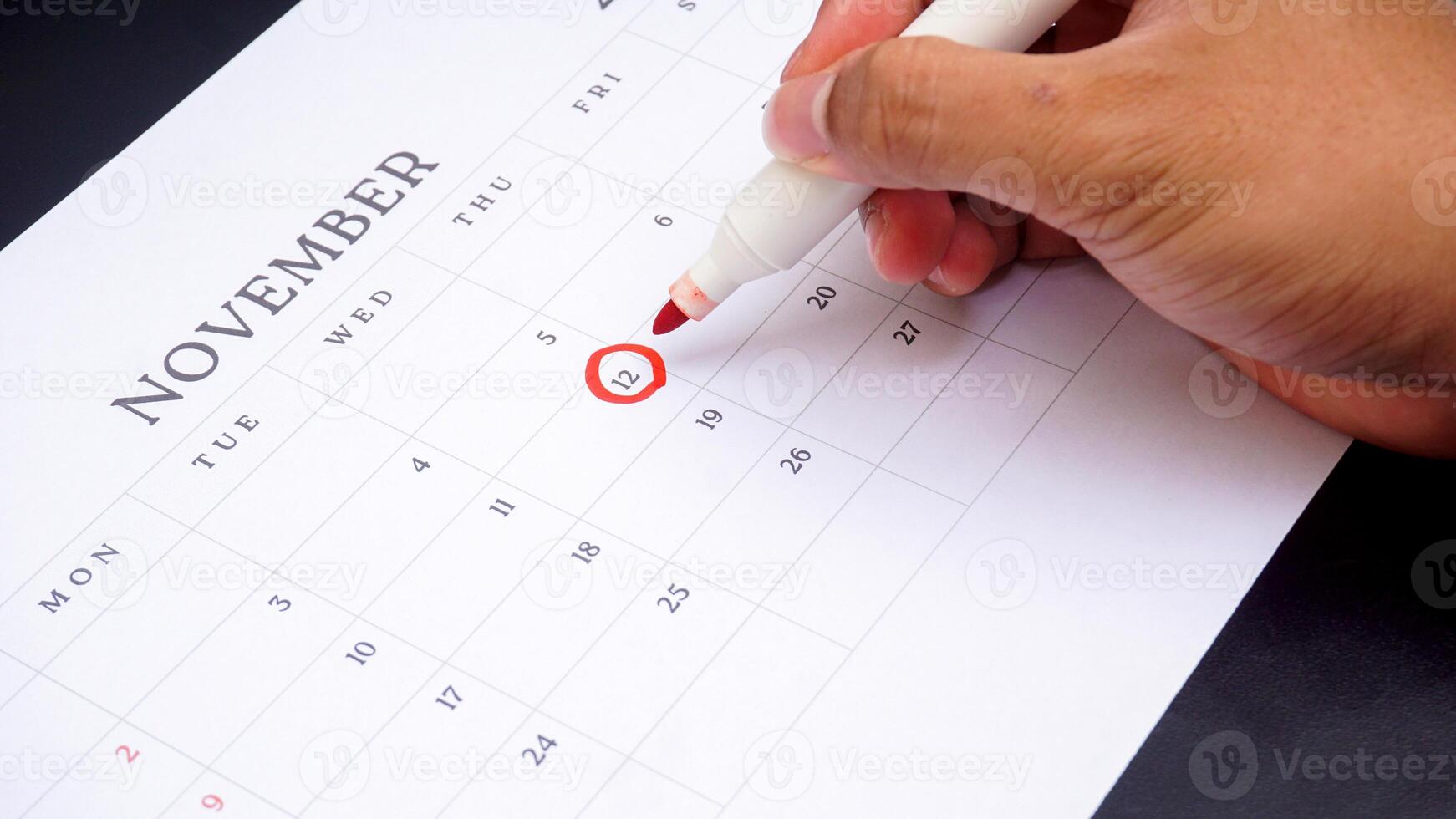 Red circle marked on a calendar at 12 of November as symbol of important day isolated on black background photo
