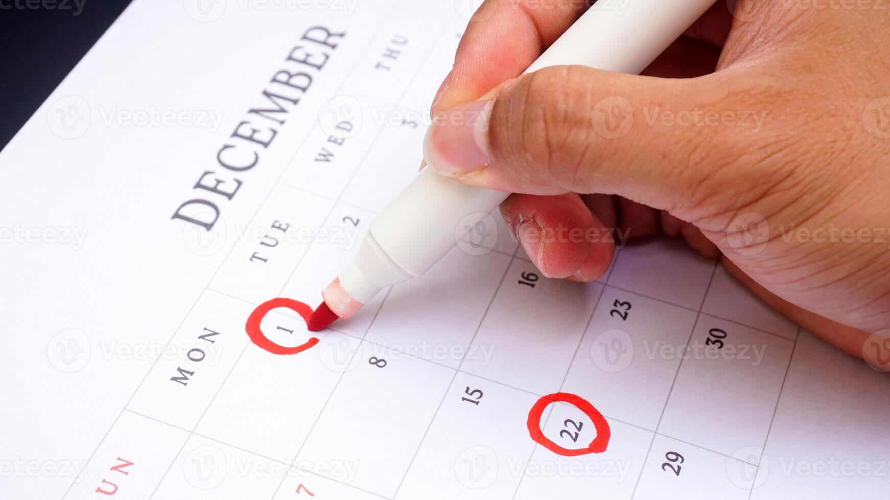 Red circle marked on a calendar at 1 and 22 of December isolated on black background for an important day photo