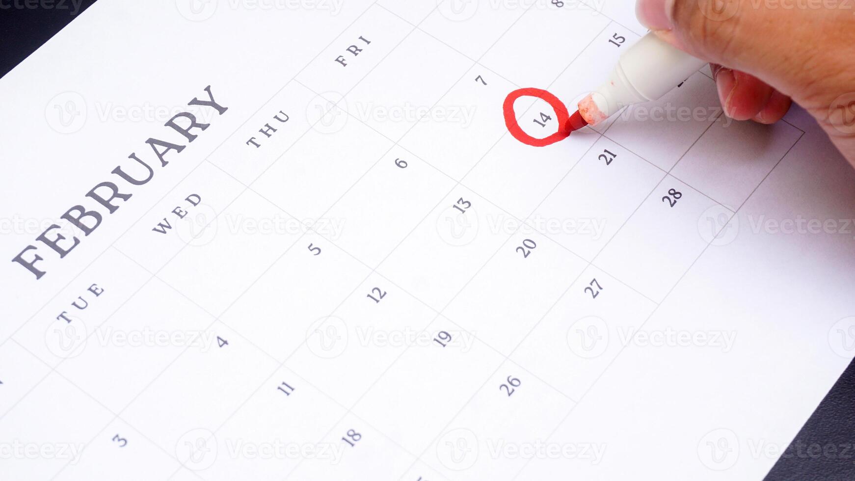 Red circle marked on calendar at 14 of February as symbol of valentine day isolated on black background photo