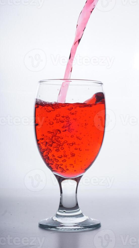 Red colored water poured into transparent glass isolated on white background photo