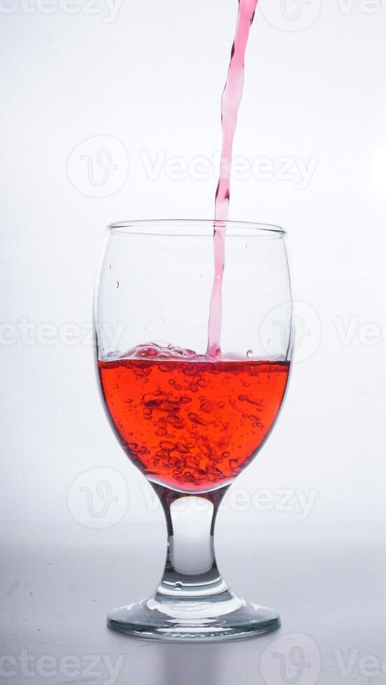 Red colored water poured into glass isolated on white background photo