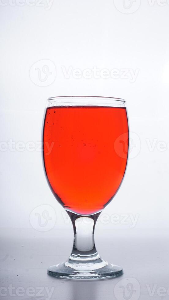 Red colored water in drinking glass isolated on white background photo