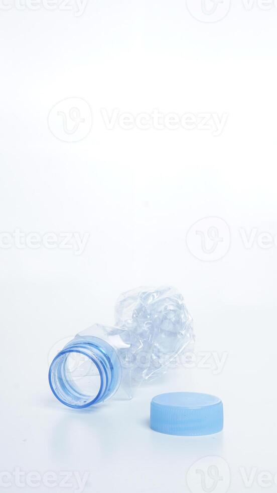 Empty crumpled plastic bottle waste with blue bottle cap isolated on white background photo