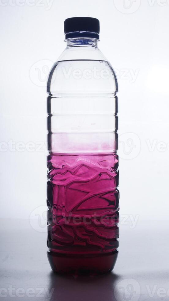 Purple colored water with gradation in plastic bottle isolated on white background photo