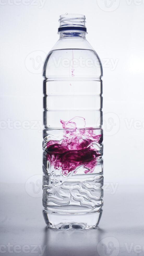 Water mixed with purple dye in plastic bottle isolated on white background photo
