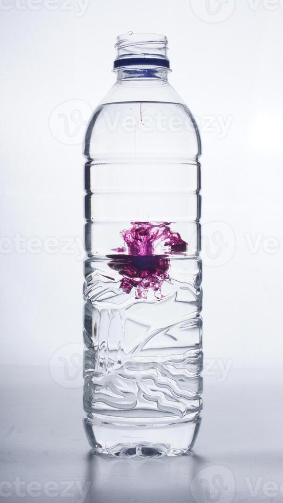 Water dripped with purple dye in plastic bottle isolated on white background photo