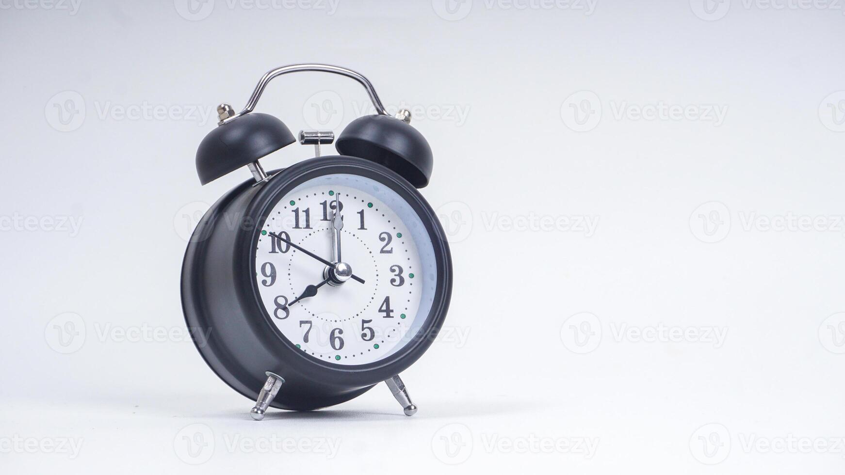 Black retro alarm clock shows 8 o'clock isolated on white background photo