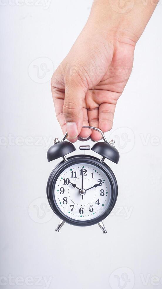 Hand holding classic black alarm clock isolated on white background photo