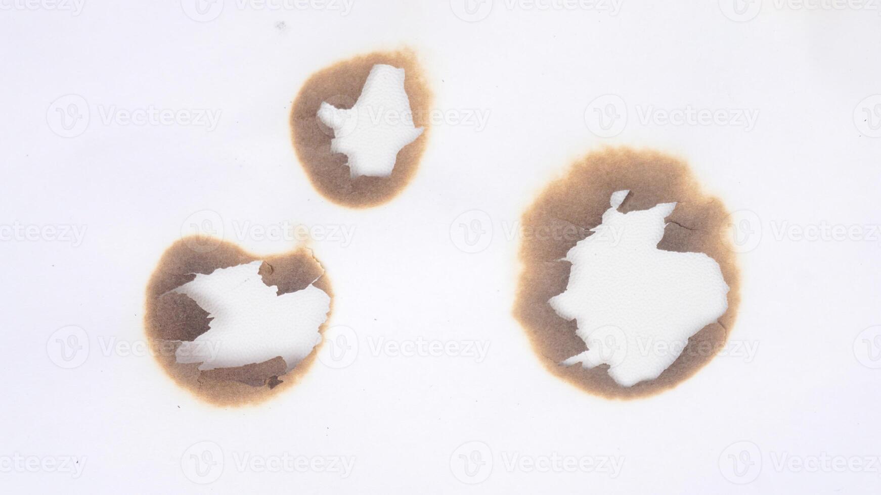 Three holes in the burned white paper isolated on white background photo