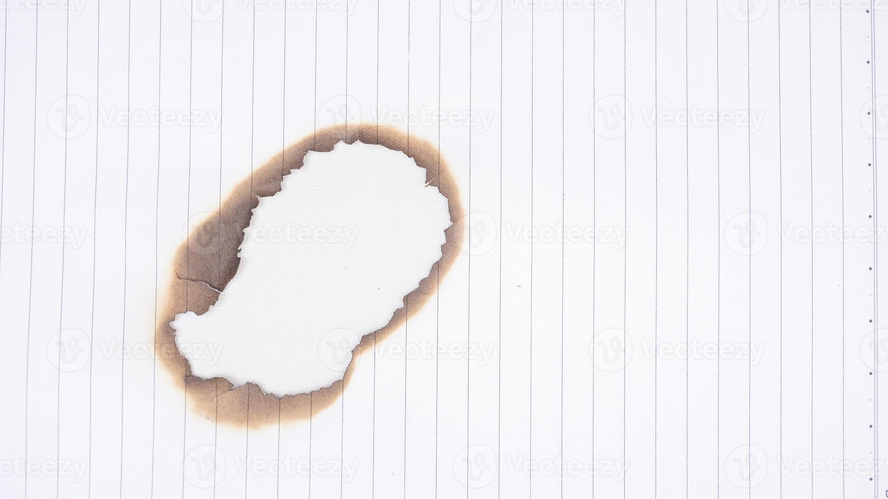 Burnt hole in white stripped paper isolated on white background photo