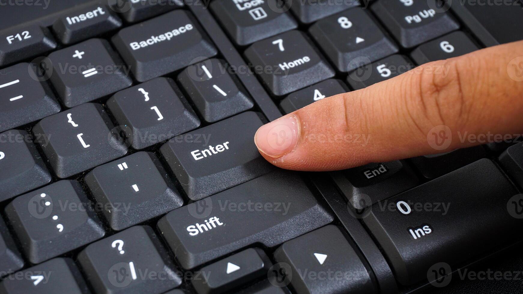 Close up on finger texting on a computer keyboard isolated on black background photo