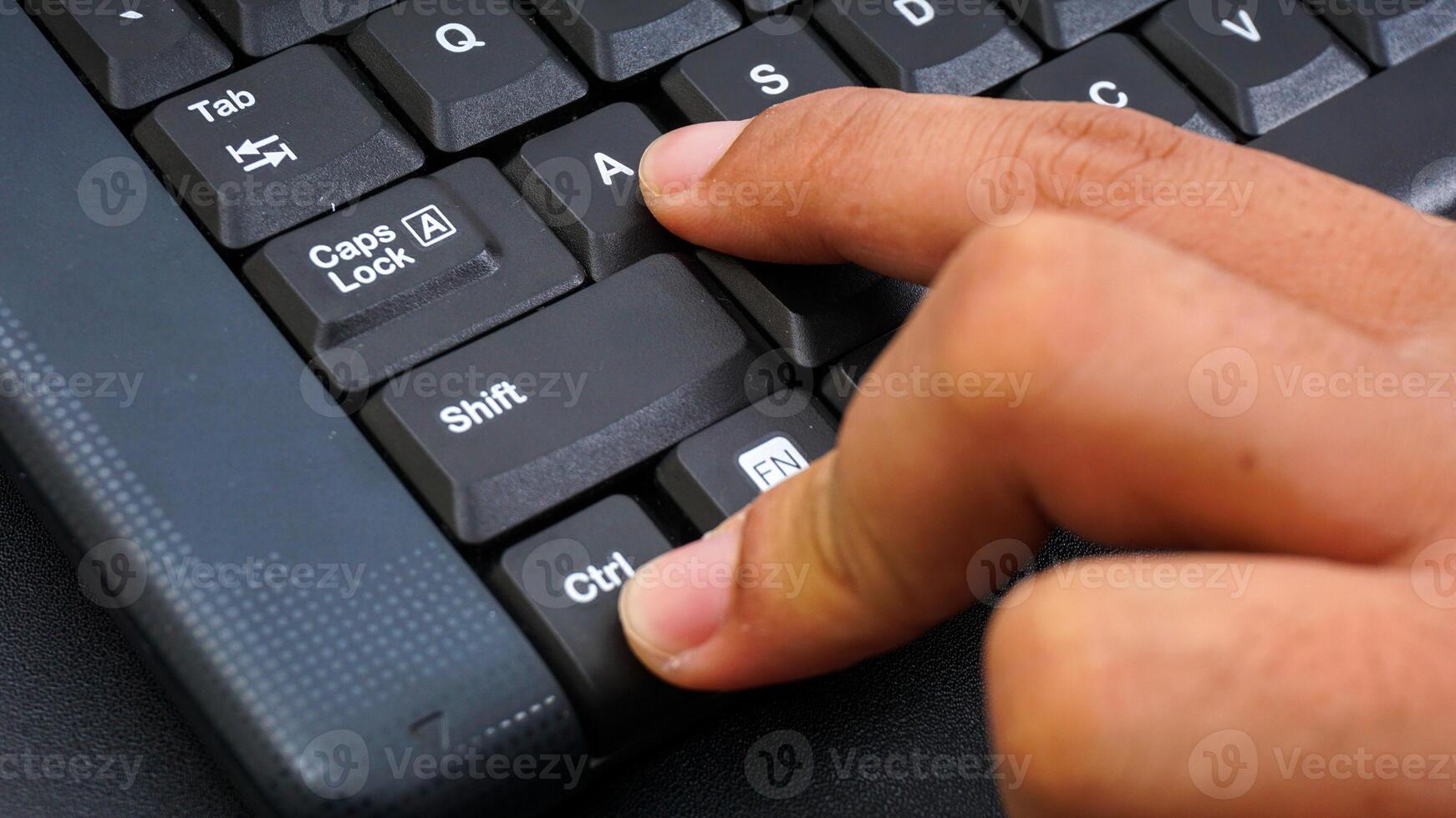 Close up on finger pressing ctrl or control and A shortcut keys on a computer keyboard for select all isolated on black background photo