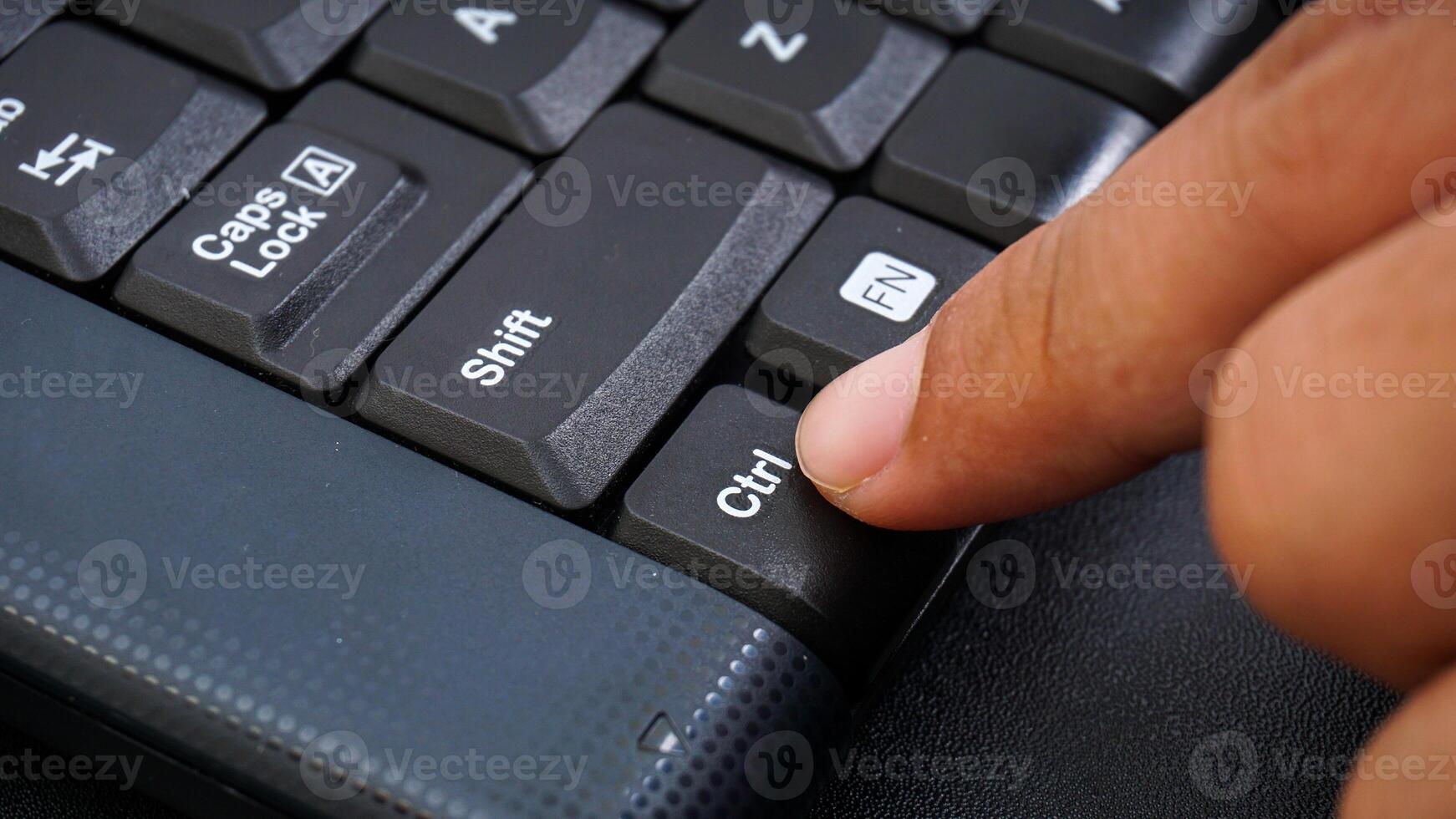 Close up on finger pressing ctrl or control button on a computer keyboard isolated on black background photo